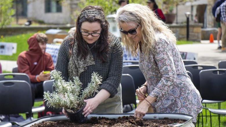 博克斯 staff member and student plant seeds in campus garden